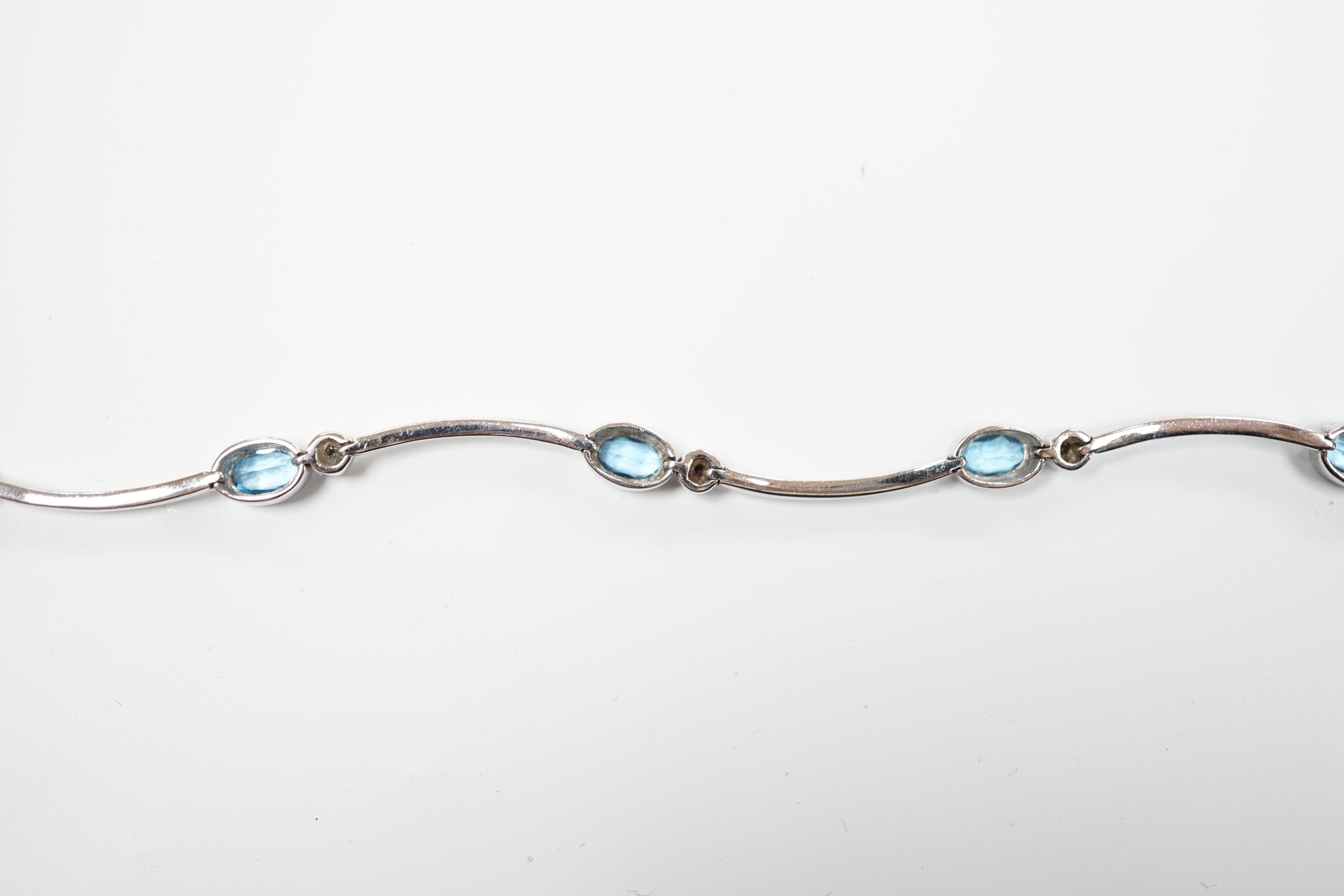 A modern 9ct white gold blue topaz and diamond chip set bracelet, 18.5cm, gross weight 9.1 grams.